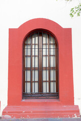 Obraz premium Classic Exterior Arch Window with Iron Bars and Red Frame Detail