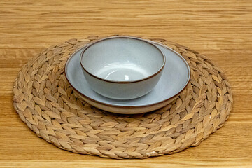Porcelain ceramic plates with circle rattan pad on wooden table