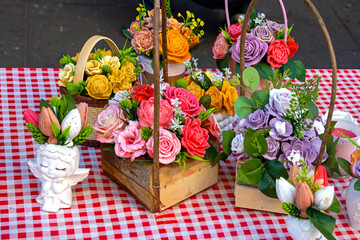 Colorful beautiful artificial flowers in wooden baskets on table inside room interior