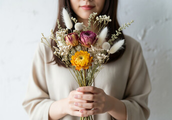 女性が大切そうに両手で抱える色鮮やかなドライフラワーの花束