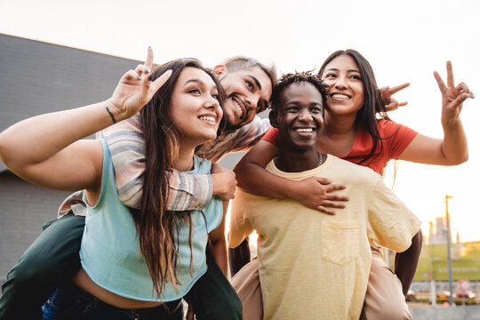 Young diverse friends have fun hugging together in the city - Friendship and diversity concept