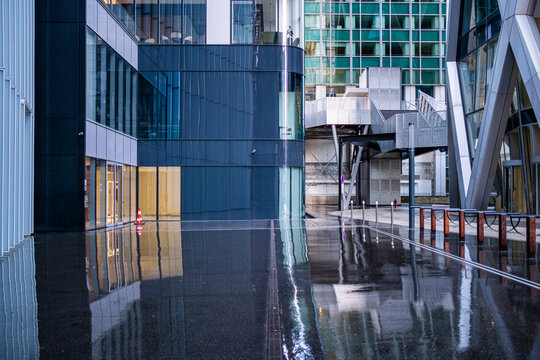 Reflection of modern glass architecture on Paris pavement plaza in La Defense corporate district creating sleek urban office scene after rain