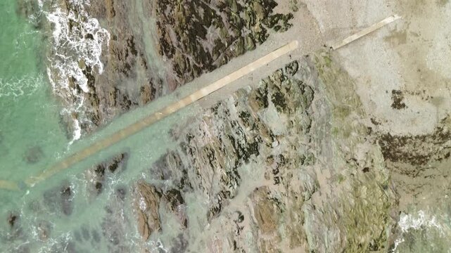 Top-down aerial video following the rocky coastline at Looe
