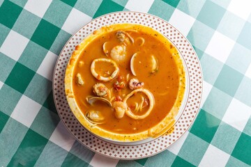 イカ、タコ、アサリ、ホタテを贅沢に使い、魚介の出汁が溶け出したシーフードのトマトソーススープパスタ。色鮮やかなトマトスープと豊富な具材が絡み合う、イタリアンレストランの看板メニューや冬の温製パスタを伝える販促・広告用素材に。 | A seafood tomato sauce soup pasta with squid, octopus, clams, and scallops in a rich 