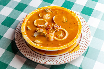 イカ、タコ、アサリ、ホタテを贅沢に使い、魚介の出汁が溶け出したシーフードのトマトソーススープパスタ。色鮮やかなトマトスープと豊富な具材が絡み合う、イタリアンレストランの看板メニューや冬の温製パスタを伝える販促・広告用素材に。 | A seafood tomato sauce soup pasta with squid, octopus, clams, and scallops in a rich 