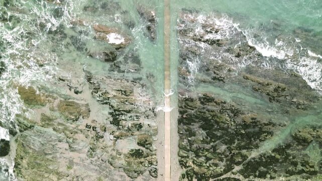 Top-down aerial video of coastal structure and shoreline at Looe