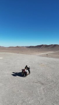 4K drone orbit shot of Mano del Desierto sculpture in Antofagasta with motorcycle riding by. Iconic desert art in Chile.