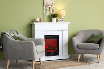 Fototapeta premium Interior of modern room with fireplace and armchairs near green wall