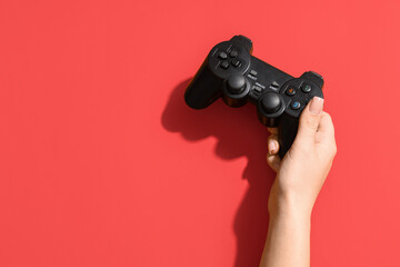Female hand with modern game pad on red background, closeup © Pixel-Shot