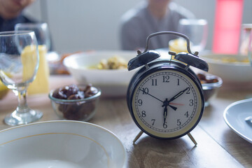 Naklejka premium Close Up Of Vintage Alarm Clock On Dining Table Waiting For Maghrib Iftar Time