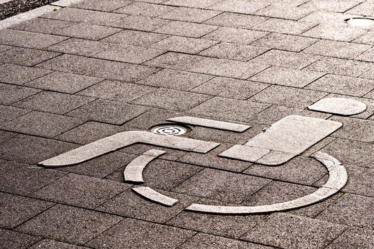 Urban concrete pavement detail with wheelchair icon and accessibility sign as disabled street marking for public inclusive design access