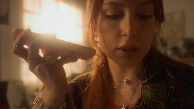 Cinematic close up shot of smiling young woman recording voice message holding phone in hand enjoying conversation with friend online, copy space