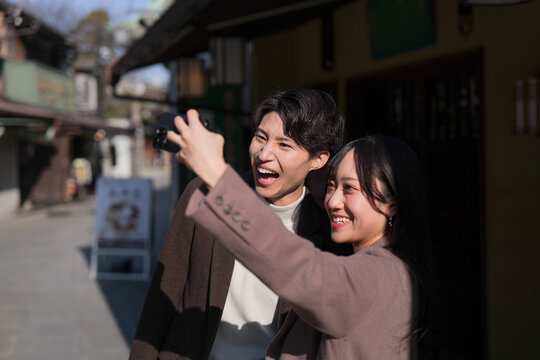 柴又の観光地で笑顔で自撮りをするカップル