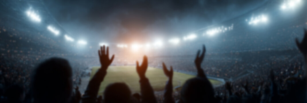 A blurry image of a football stadium filled with cheering fans in red uniforms, with a bright green lawn in the background.