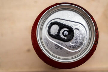 Close-up of a wet red aluminum can with a black pull tab, on a dark background. Perfect for themes of recycling, beverages, and sustainability.
