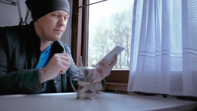 Peaceful Train Journey: Man Enjoying Tea, Video Chatting, and Soaking in the Scenic Views