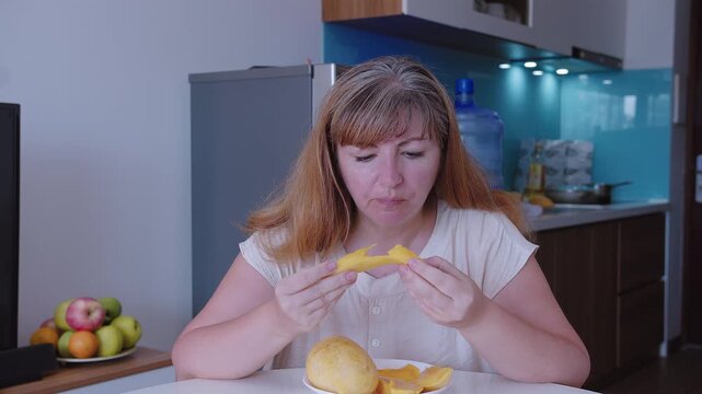 Woman eats a ripe mango, sliced into slices