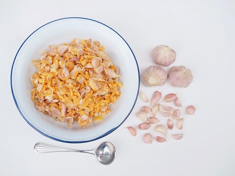 Golden fried garlic is in a bowl placed on a white surface.