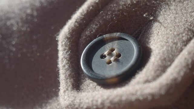 Close-up of a black button on a brown fabric surface