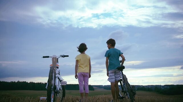 Sunset Embrace: Children Sharing a Heartfelt Hug After an Exciting Bike Ride Through the Field