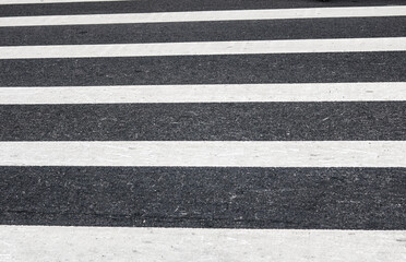 A bold, high-contrast perspective of a pedestrian crosswalk. The alternating stripes of crisp white paint and dark charcoal asphalt create a powerful geometric rhythm.