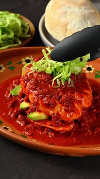 Placing chopped lettuce on top of a chancla poblana or Mexican pambazo, Mexican traditional food