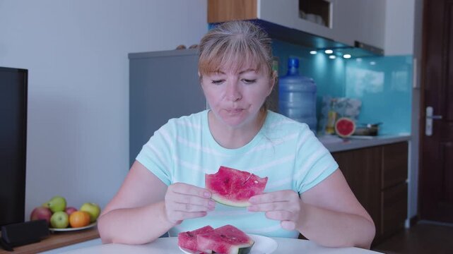 Portrait of a woman eating watermelon sitting at a table