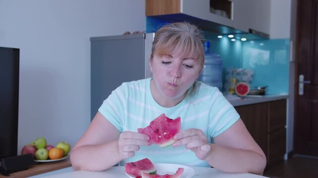 Woman eating watermelon sitting at a table