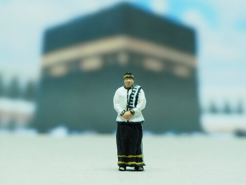 Mini toy of action figure at outdoor with blurred background. Miniature photography concept design. Minifigure of muslim character pray at Masjid. Ramadan ied al fitr and al adha at mataf