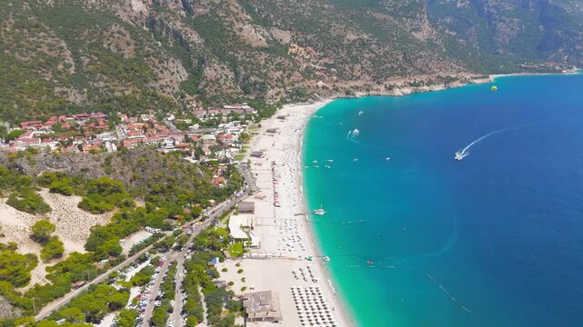 Oludeniz, Turkey. Aerial drone view from above of a yellow parasail over a speedboat on turquoise sea, Oludeniz Beach and mountain coastline in background, summer.. Aerial View