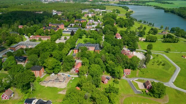 Aerial flyover with tilt down above Restad Gard campus buildings and Holzhausens park near Gota alv river in Vanersborg, Sweden