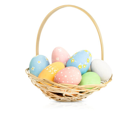 painted Easter eggs in a wicker basket on a white isolated background