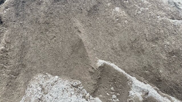 A pile of fine sand as a building construction material with a clearly visible natural texture, suitable to describe the basic material for concrete and plastering work.