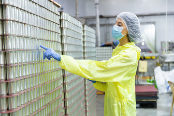 Quality control worker inspecting stacked canned fish products in seafood factory warehouse....