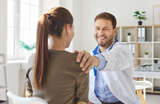 Positive man doctor or nurse holds medical consultation for patient in hospital office or medical office, offering care and support during visit in a professional setting with compassion.