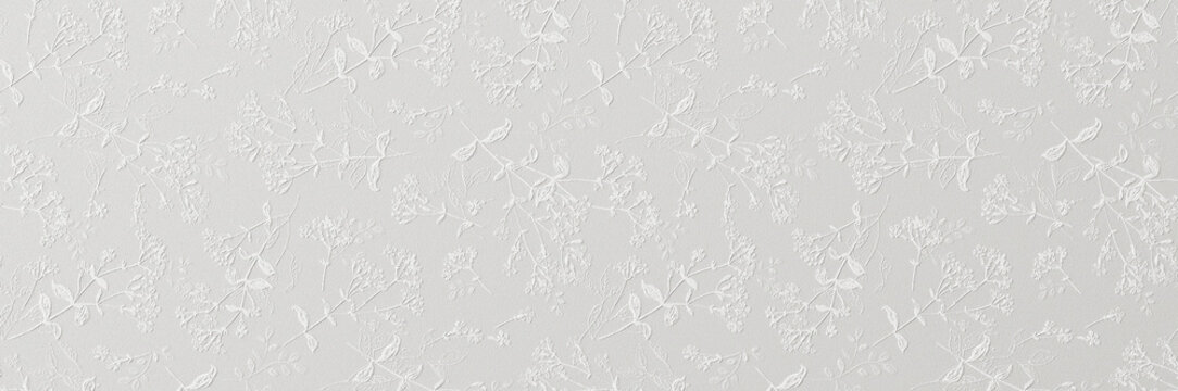 A subtle white embossed floral pattern with delicate leaves and blossoms creating an elegant textured wallpaper background.