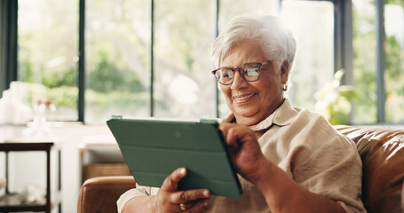 Obraz premium Scrolling, smile and tablet with old woman on sofa in home for retirement or social media. App, glasses and search with happy senior person in living room of apartment for browsing or reading