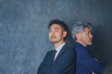 背中合わせで立つスーツ姿の男性