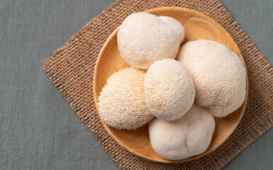 Fresh Lion's Mane mushroom on wooden plate (Hericium erinaceus), known for nootropic benefits and medicinal properties © nungning20