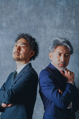 背中合わせで立つスーツ姿の男性