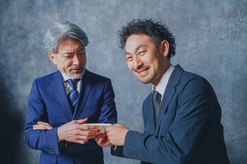 札束を渡すスーツ姿の男性