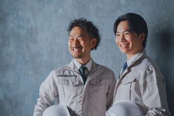 ヘルメットを持った作業着姿の男性