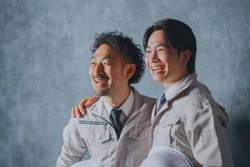 肩を組む作業着姿の男性