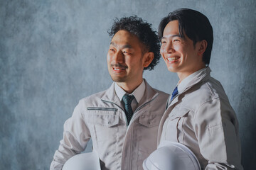 ヘルメットを持った作業着姿の男性