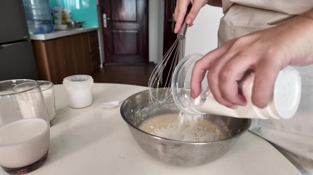 Woman adds ingredients to the beaten eggs for cooking the dish. Makes morning pancakes