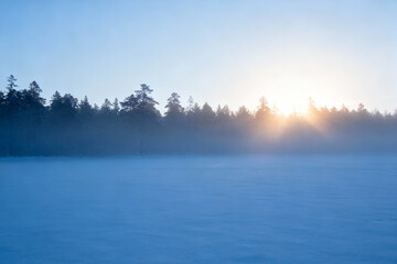 Sunrise over frozen lake with trees
