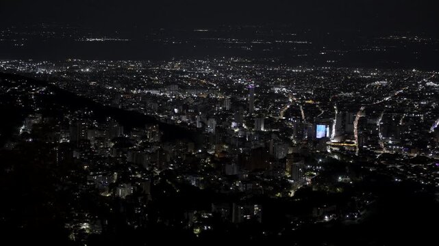 Slow left-to-right camera pan showing a wide nighttime view of Cali. The footage captures illuminated buildings, city lights and urban skyline, highlighting the vibrant atmosphere and metropolitan lan