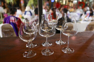 Collection of empty wine tasting glasses ready for celebration on wooden table. blurred background shows festive party event with people enjoying evening