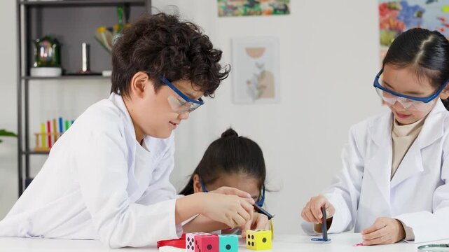 Asian Elementary Students in Lab Coats Conducting Science Experiment with Magnets