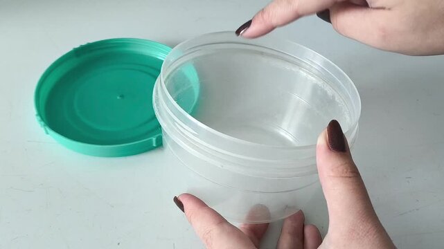 A woman's hand touches the edge of a plastic container with her finger. Microplastics in food. Reusable food containers